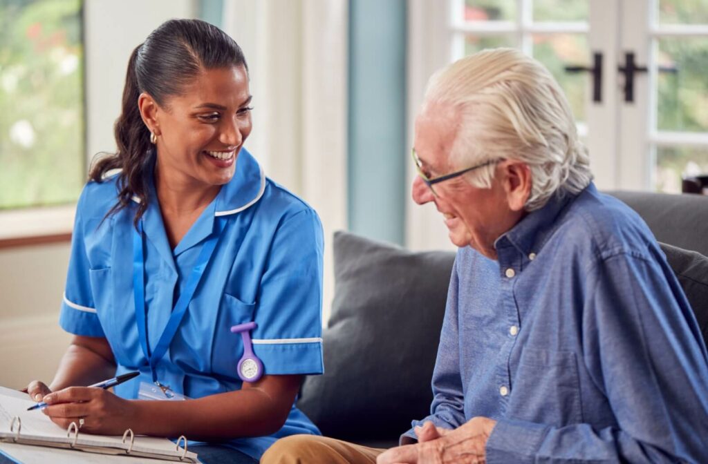 A nurse and a senior smiling and laughing while speaking about health care in an assisted living facility