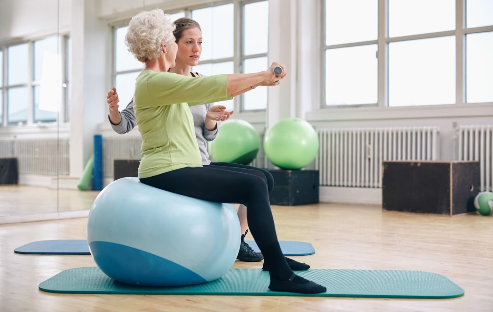 A trainer offers support to an older adult while practicing balance exercises.
