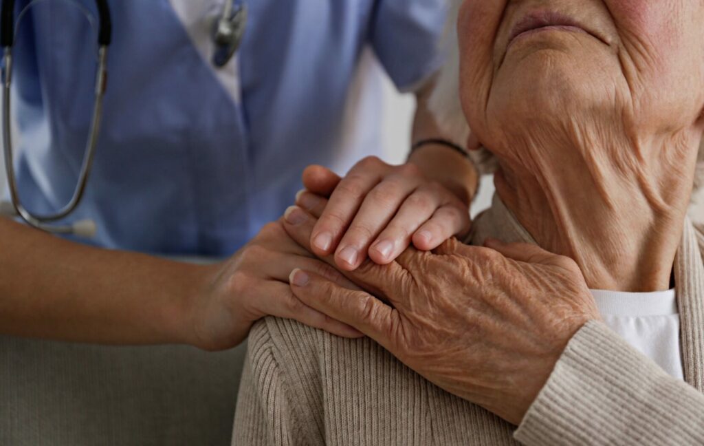 A caregiver resists their hands on the shoulder of a senior resident