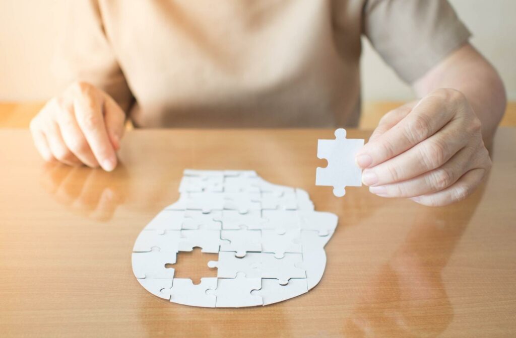 a person building a puzzle in the shape of a human head side-profile, with one piece missing - symbolizing dementia