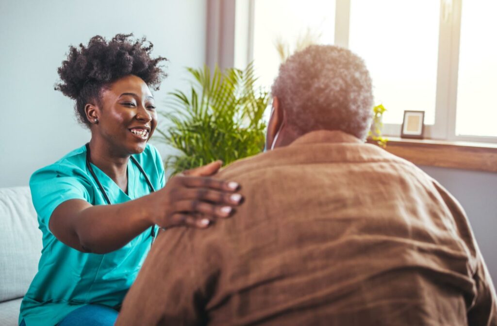 a carer places their hand on the shoulder of a senior in support